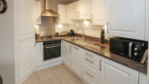Una cocina moderna con armarios blancos, electrodomésticos de acero inoxidable y encimera de madera.