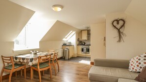 A cozy, well-lit room with a dining area, kitchenette, and a living space. - 10 Monarch Country Apartments (Newtonmore)