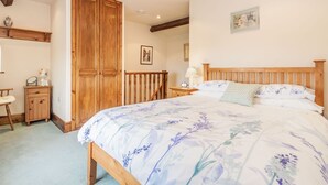 A bedroom with a wooden bed, a nightstand, a dresser, and a large wooden wardrobe. - Green Clough Farm (Bradford)