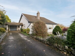 A two-story house with a garage, a stone wall, and a driveway leading to the front door.