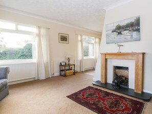 A living room with a fireplace, a sofa, a rug, and a painting of boats on the wall.