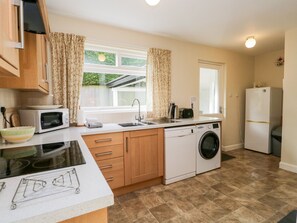 A compact kitchen with a microwave, toaster, sink, and washing machine. - Silverdale Mount (Grange-over-Sands)
