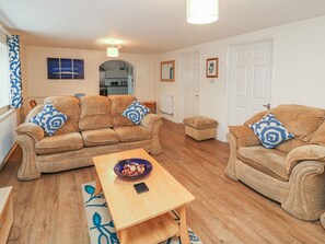 A living room with two beige sofas, a wooden coffee table, and a patterned rug. - Old Sweet Shop (Louth)