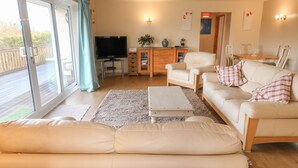 A living room with a sofa, armchairs, a coffee table, and a TV. - Clovermead Cottage (Derby)