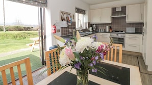 A modern kitchen with a dining area, a view of the garden, and a fire extinguisher on the wall. - Waddleduck (Whitby)