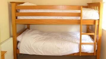 A bunk bed with three levels, each with a pillow and white bedding.