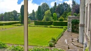 A view of a well-manicured lawn with a stone pathway leading to a building with classical architecture. - Cook's Flat (Wrexham)