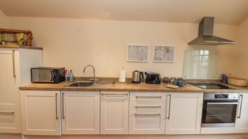 A kitchen with a microwave, sink, toaster, kettle, and oven.