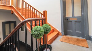 A staircase with wooden railings, a door labeled "COOK'S FLAT," and a small potted plant. - Cook's Flat (Wrexham)