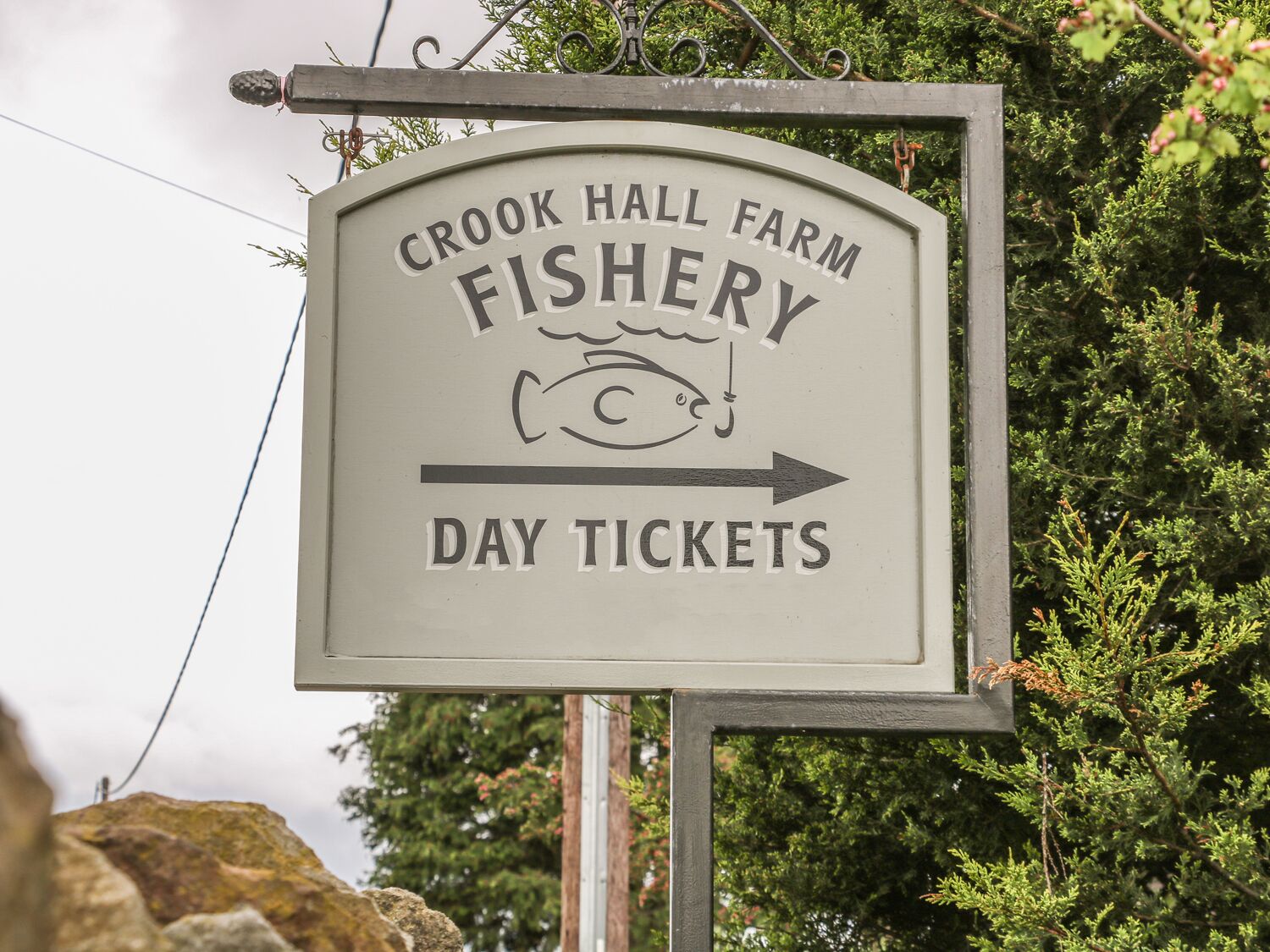 A sign for Crook Hall Farm Fishery with an arrow pointing to the right, indicating the direction to day tickets.