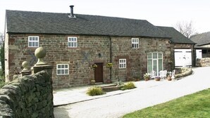 Un bâtiment en pierre avec un toit en pente, une cheminée et un garage.