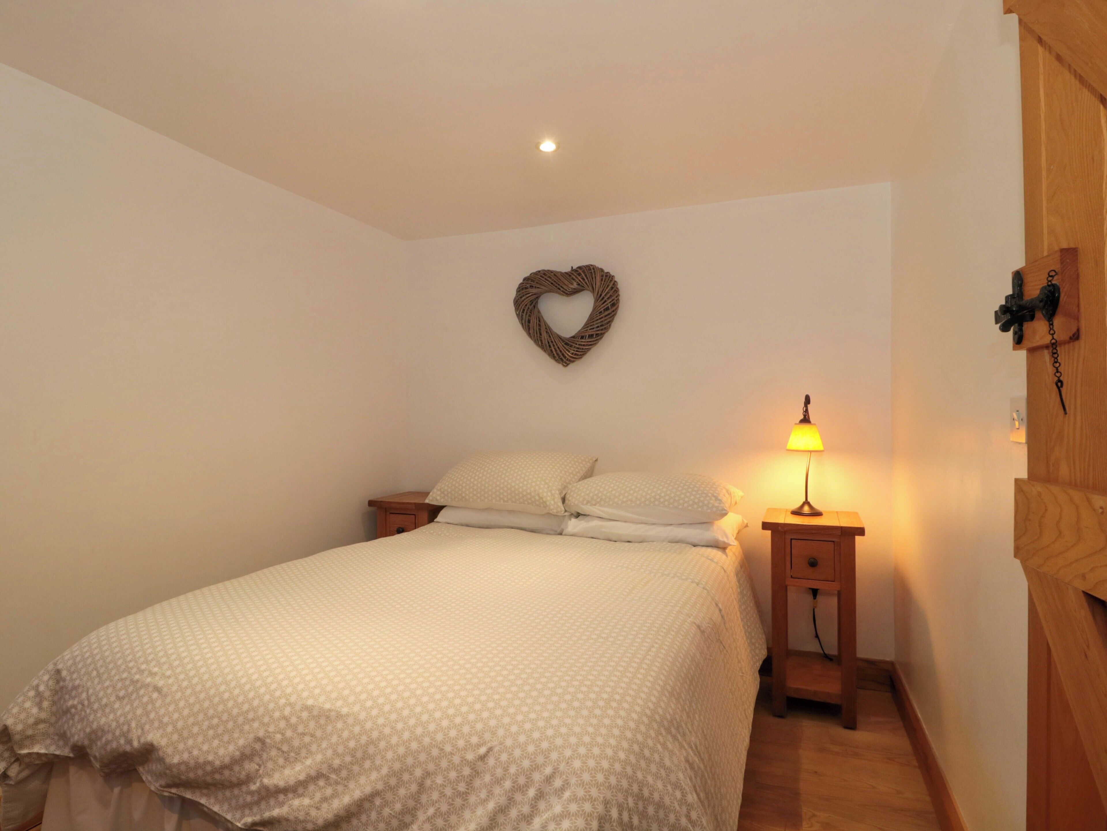 Une chambre à coucher avec un lit, une table de chevet, un décor mural en forme de cœur et une lampe de chevet.