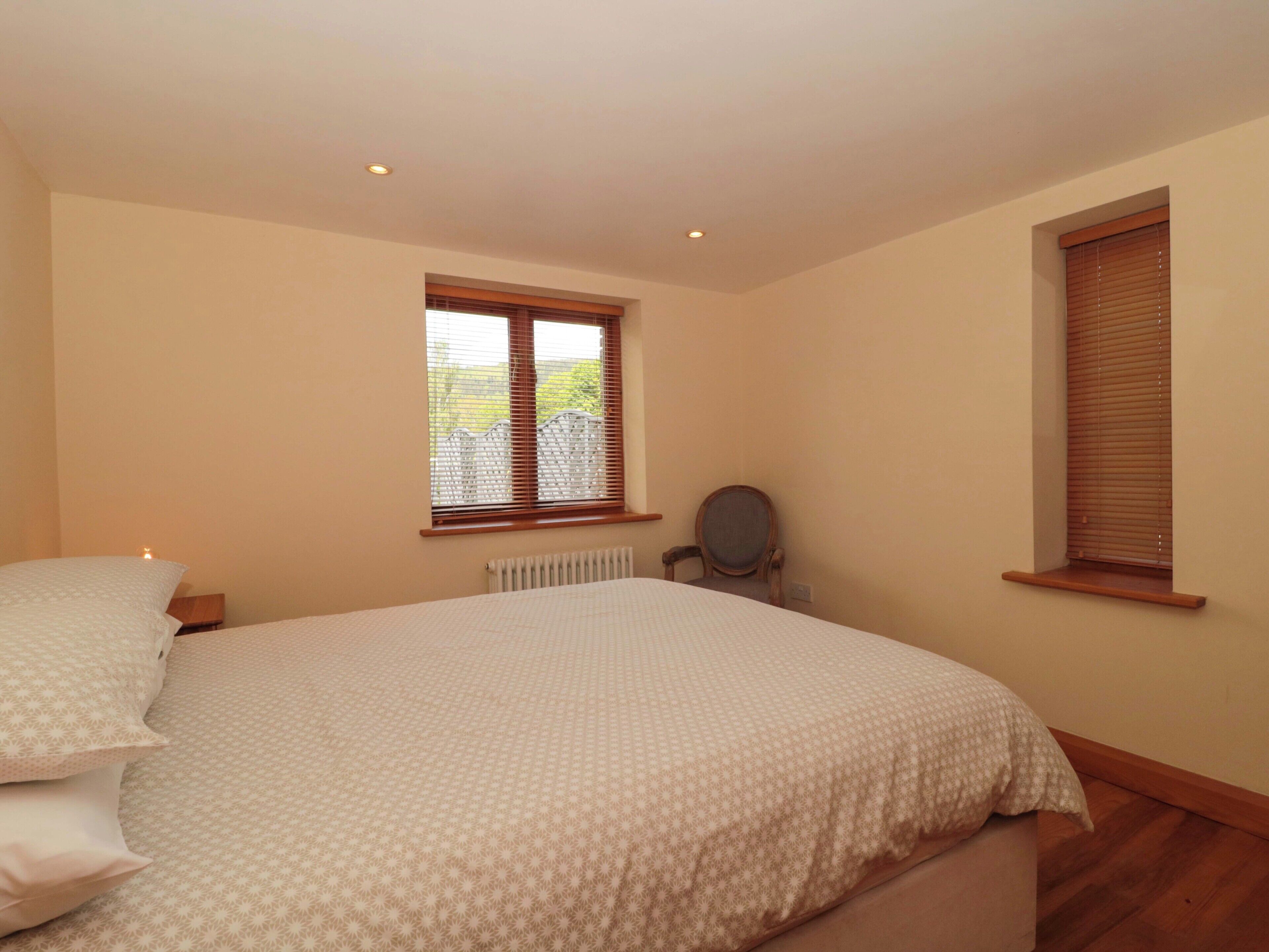 A bedroom with a bed, a chair, a window, and a radiator.