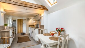 A compact kitchen with a dining area, wooden beams, a staircase, and a view of the outdoors. - Owl's Nest (York)
