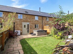 A stone house with a small garden, a hot tub, and a wooden deck. - Cow Byre (Chipping Norton)