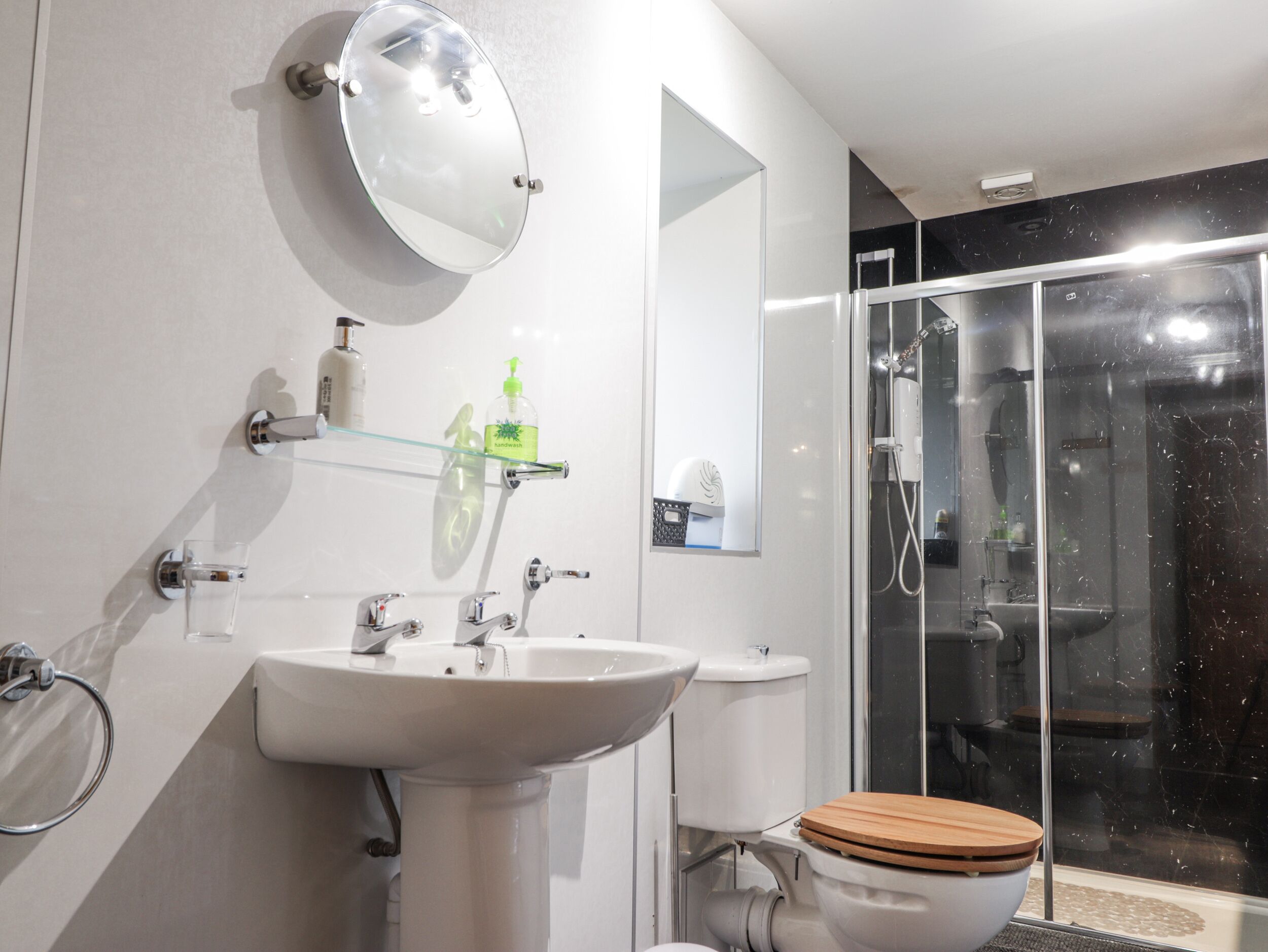 A modern bathroom with a white sink, mirror, and toilet.