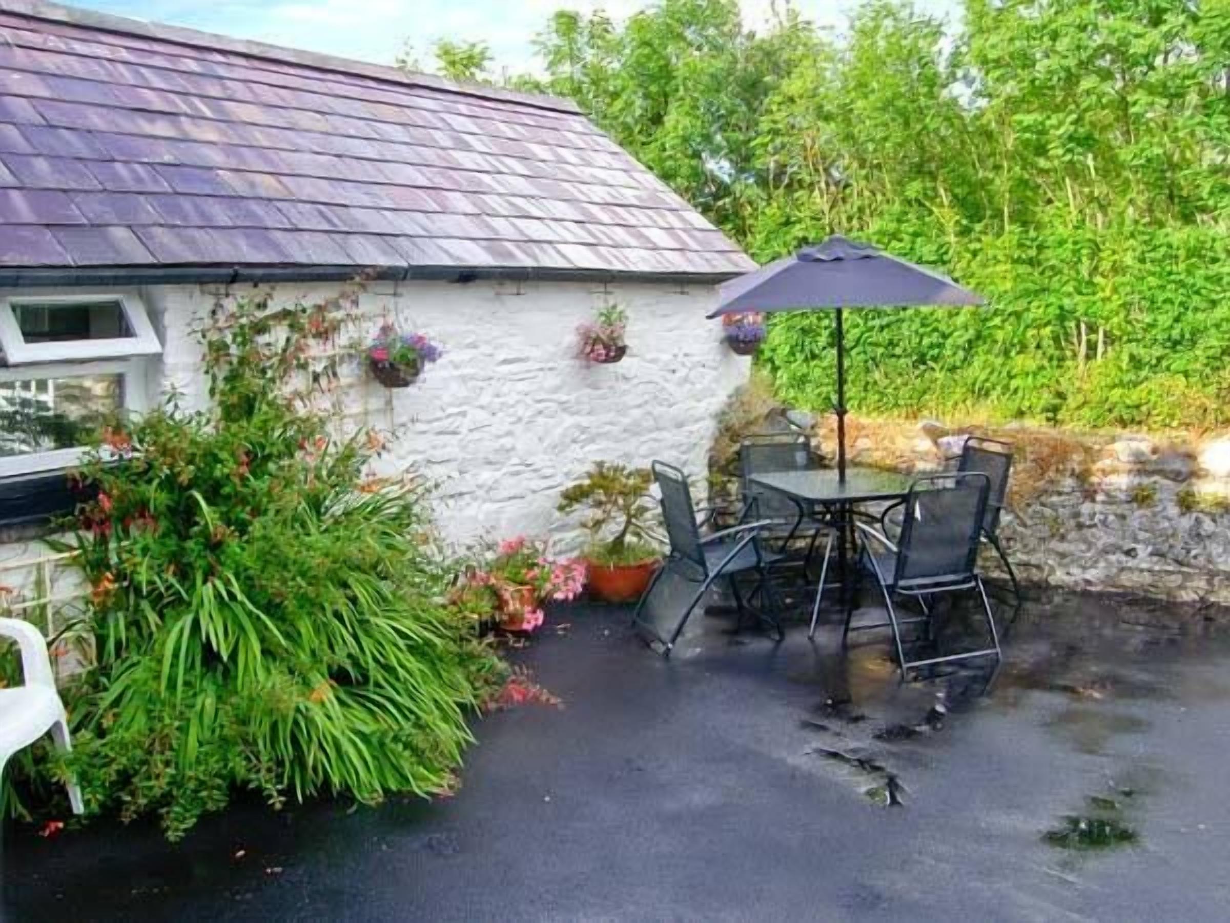 A patio area with a table and chairs, surrounded by potted plants and a stone wall.