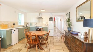 A kitchen with a dining table, chairs, a stove, a refrigerator, and a cabinet. - Mill Lodge, Brisley Accessible Norfolk Cottage Sleeping 6, Dog-friendly (Dereham)