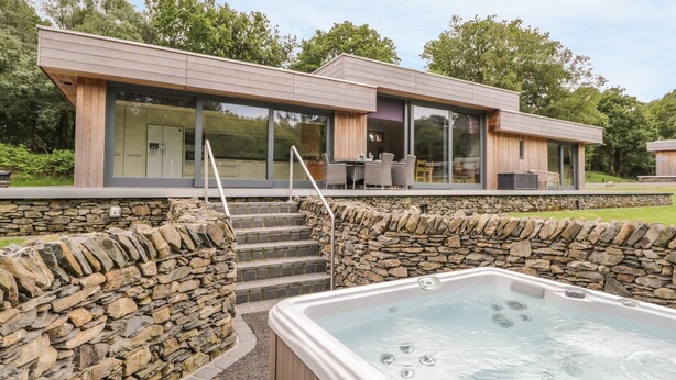 Una casa moderna con un muro de piedra, un jacuzzi y una zona de patio.