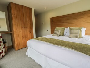 A hotel room with a large bed, wooden wardrobe, and a mirror. - Neddy Cut (Ulverston)