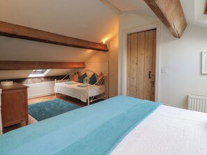 A bedroom with a bed, a wooden wardrobe, a small table, and a window.