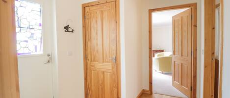 Un pasillo con puertas de madera y una pared blanca.