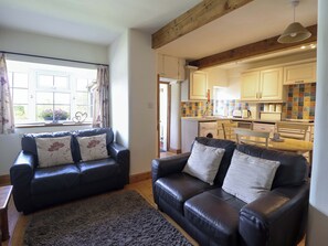 A living room with two black leather sofas, a grey rug, and a window with curtains.