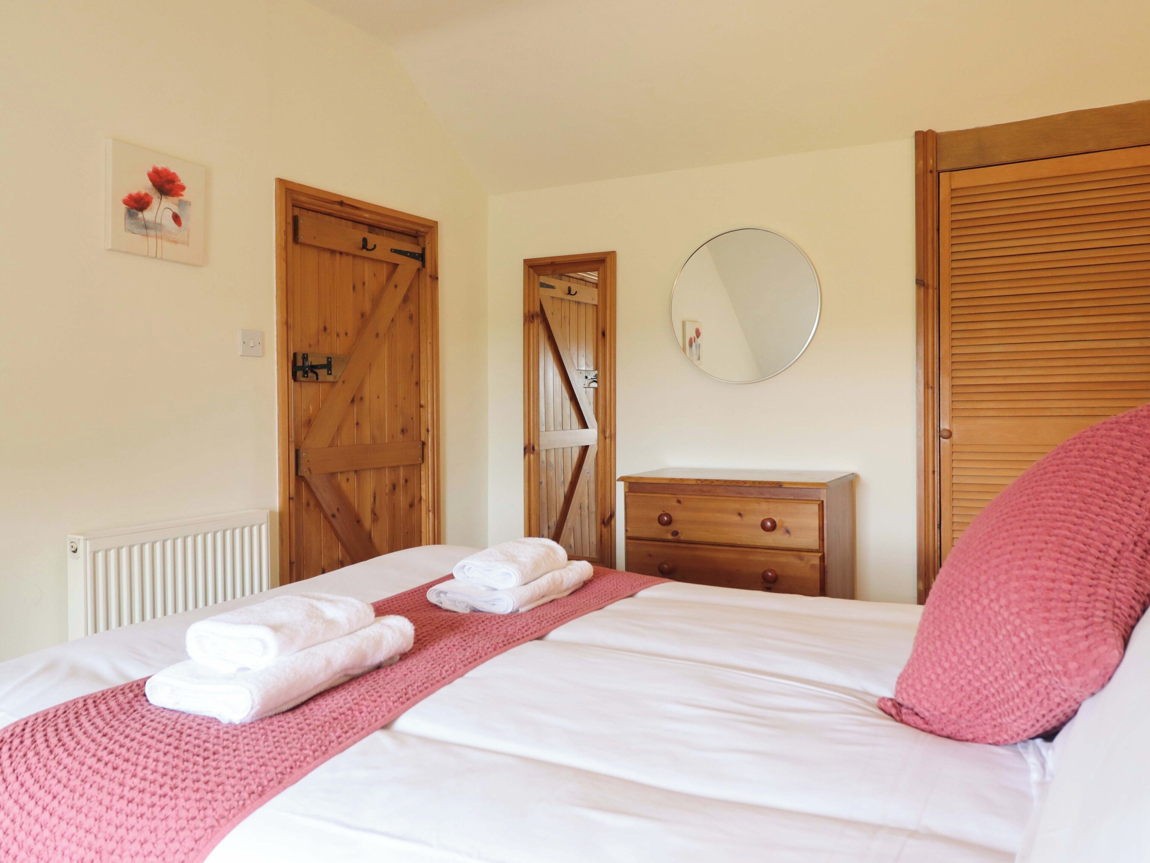 Une chambre à coucher avec un lit, une commode, un miroir et des portes en bois.