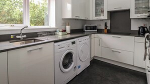 Une cuisine moderne équipée d’un lave-linge, d’un four à micro-ondes et de placards.