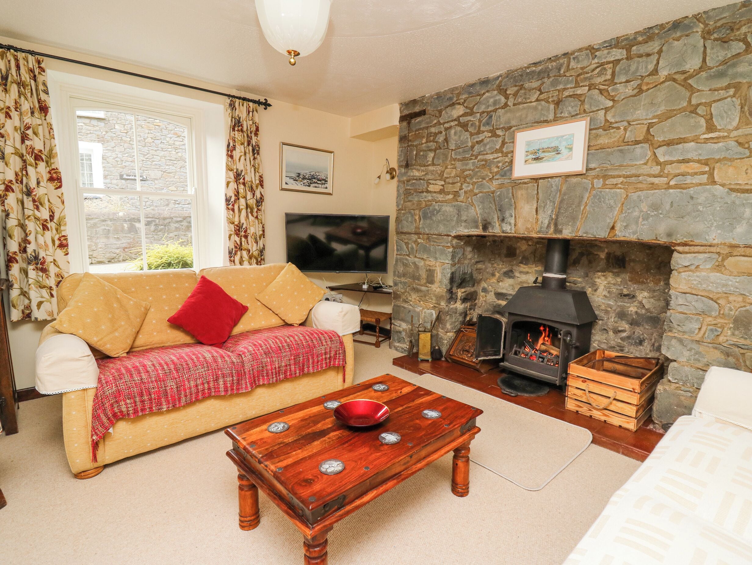 A cozy living room with a stone fireplace, a sofa, a coffee table, and a television.