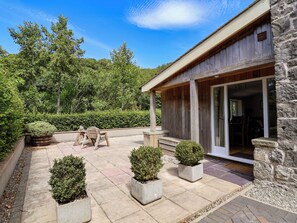 A wooden building with a covered patio area, stone walls, and potted plants. - The Lambing Shed (Rhyl)