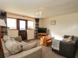 A living room with a sofa, a coffee table, a television, and a door leading to a balcony.