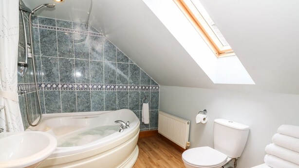 Een moderne badkamer met een vrijstaand bad, toilet en wastafel.