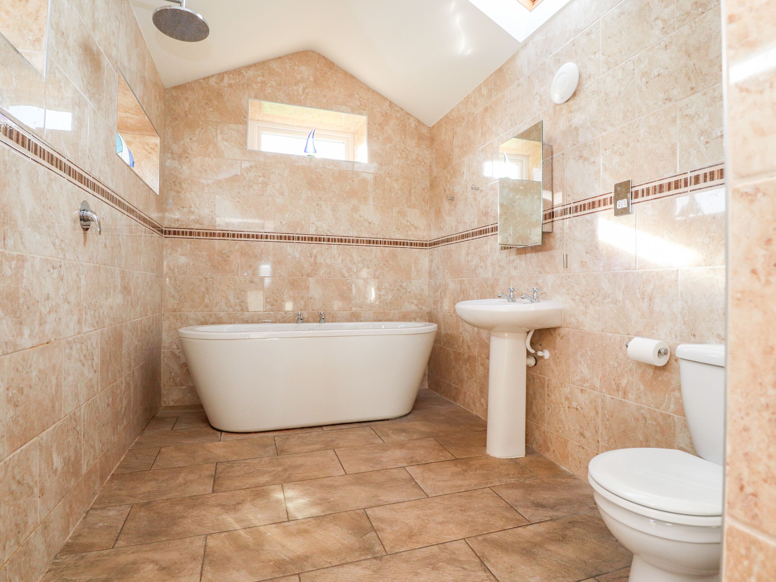 A bathroom with a freestanding bathtub, a pedestal sink, and a toilet.
