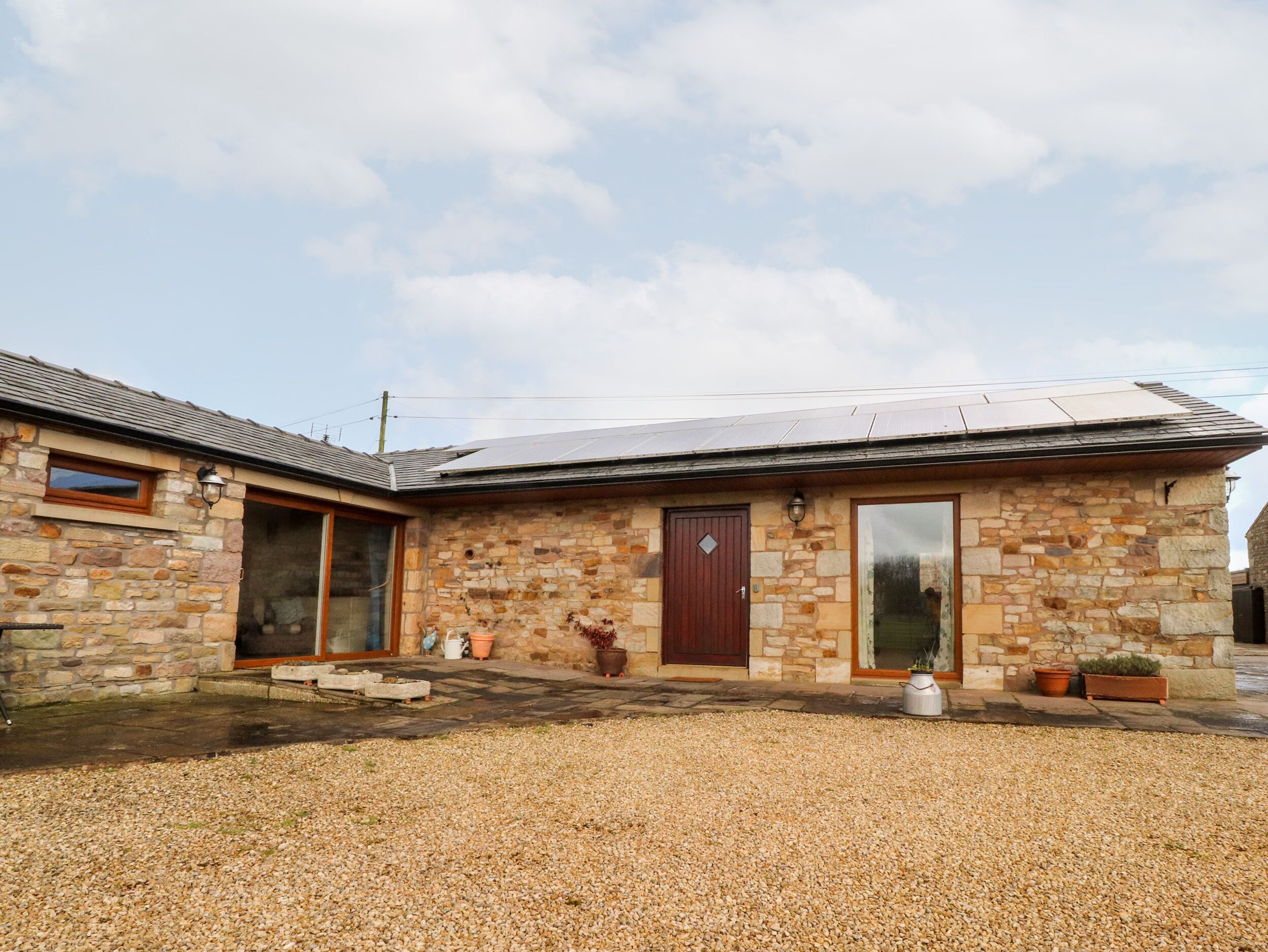 A stone building with a red door, a window, and a solar panel on the roof.