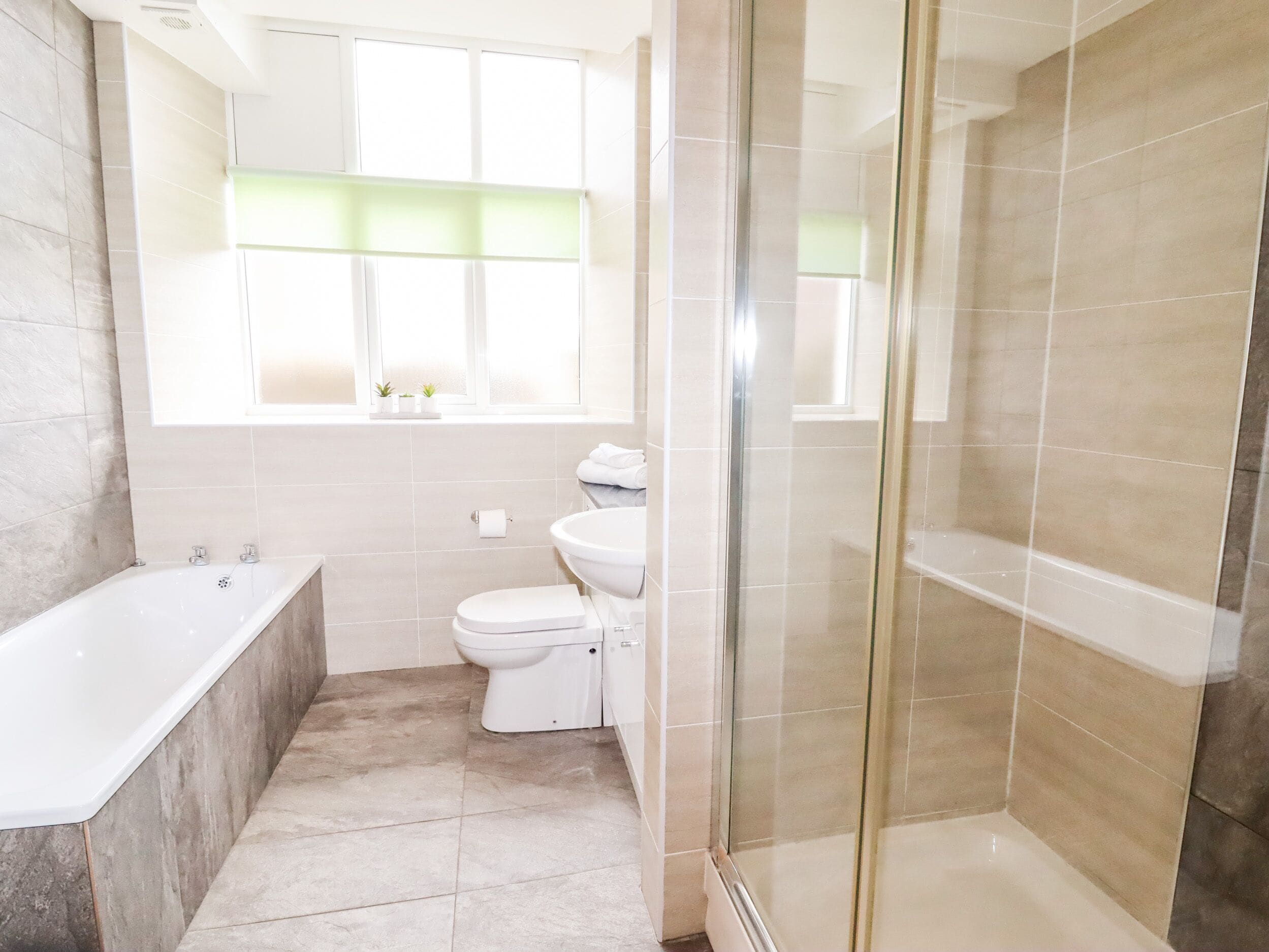 A modern bathroom with a bathtub, toilet, and glass-enclosed shower.