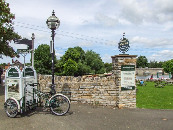 A stone wall with a sign for Avon Boating, a bicycle, and a signpost indicating directions to the boats.