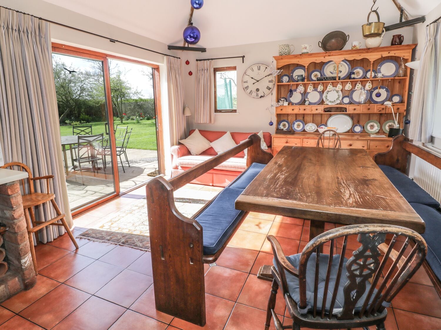 A cozy dining area with a wooden table and benches, surrounded by a variety of plates and kitchenware on shelves.