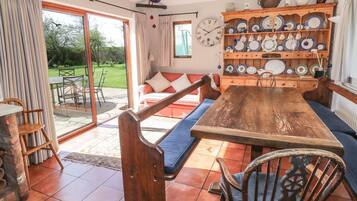 A cozy dining area with a wooden table and benches, surrounded by a variety of plates and kitchenware on shelves.