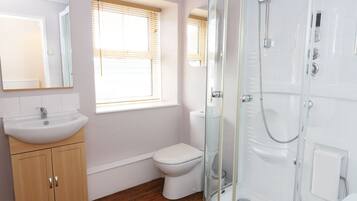Un baño con lavabo, inodoro y ducha con mampara de vidrio.