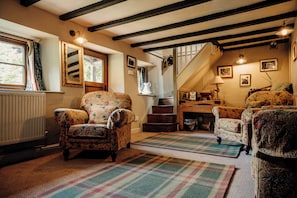 A cozy living room with floral-patterned armchairs, a wooden staircase, and a radiator.