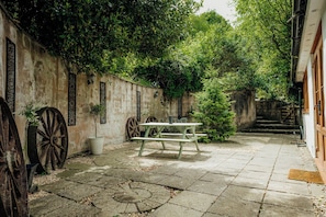 A courtyard with a picnic table, decorative wheels, a wall with lattice windows, and a staircase.