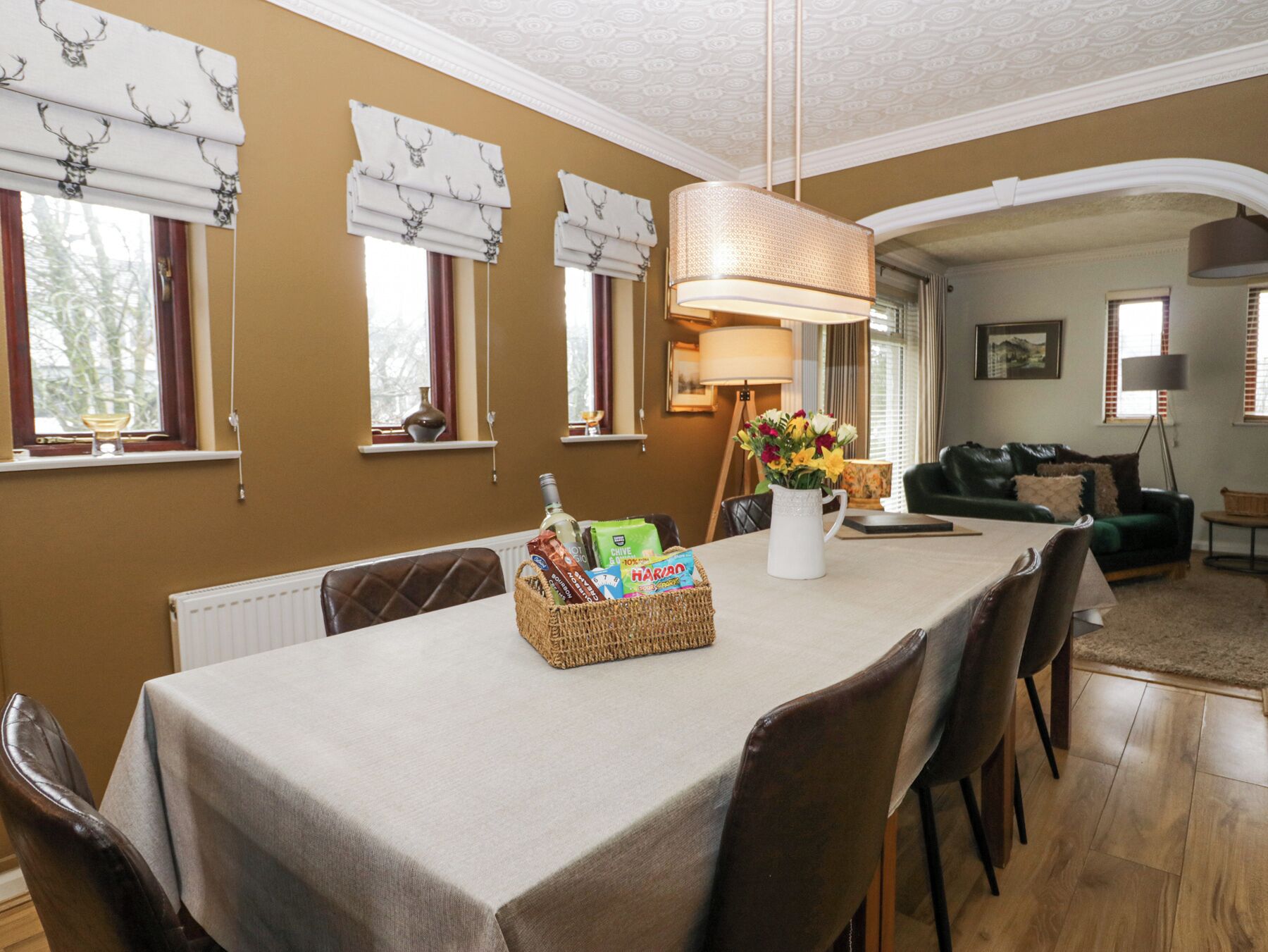Zona pranzo con tavolo apparecchiato per quattro persone, un lampadario e un vaso con fiori.