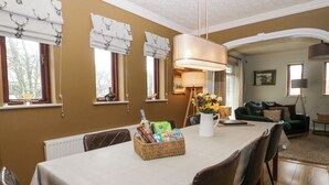 A dining area with a table set for four, a chandelier, and a vase with flowers. - Sandown (Windermere)