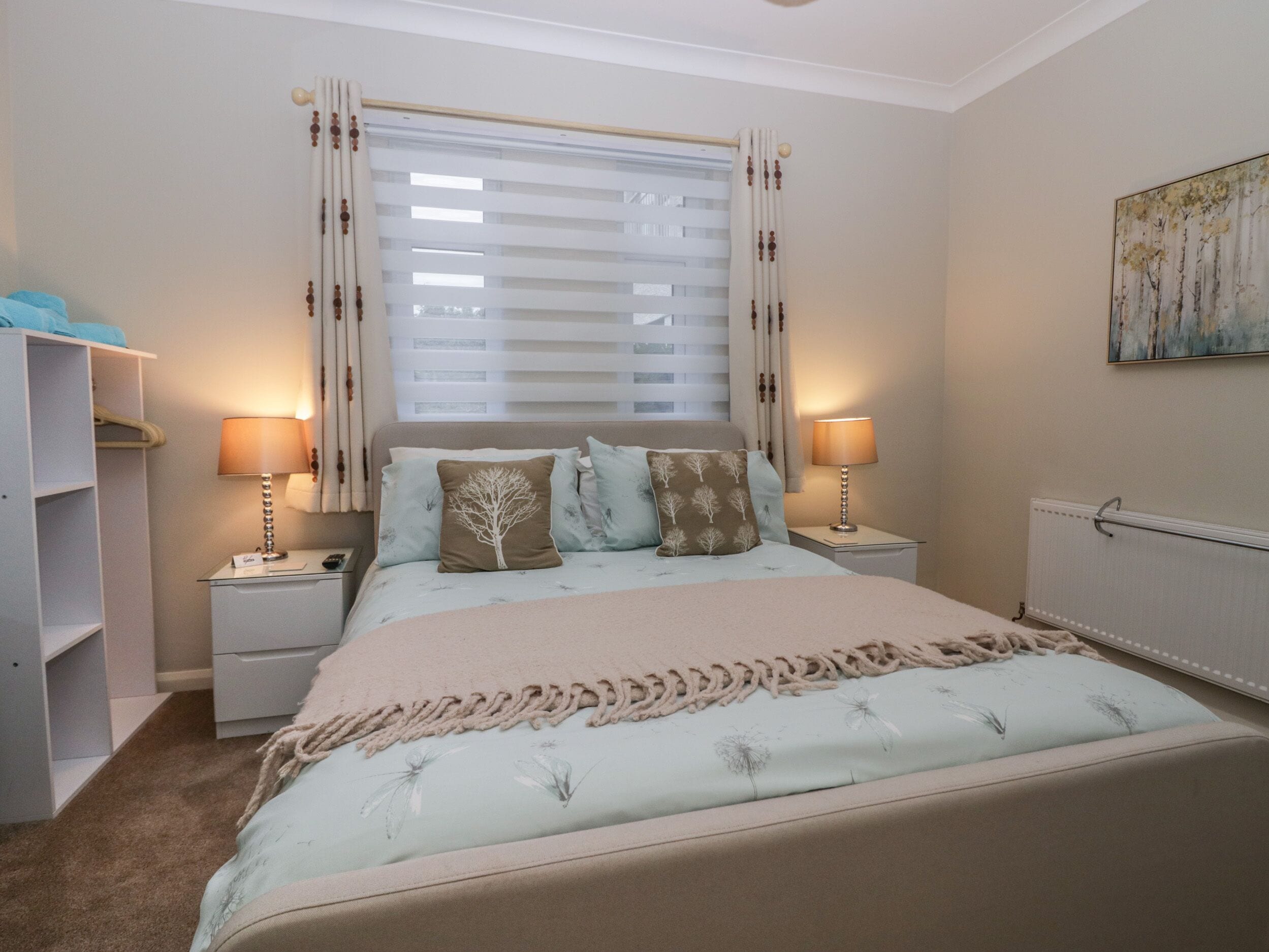 A bedroom with a bed, two bedside tables, a nightstand, a wardrobe, and a radiator.