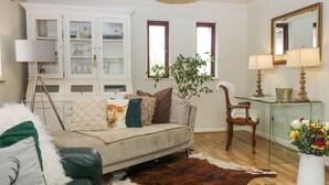 A living room with a sofa, a coffee table, a glass cabinet, a chair, and a potted plant. - Sandown (Windermere)