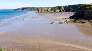 A beach with a clear view of the ocean and cliffs. - The Grange (Haverfordwest)