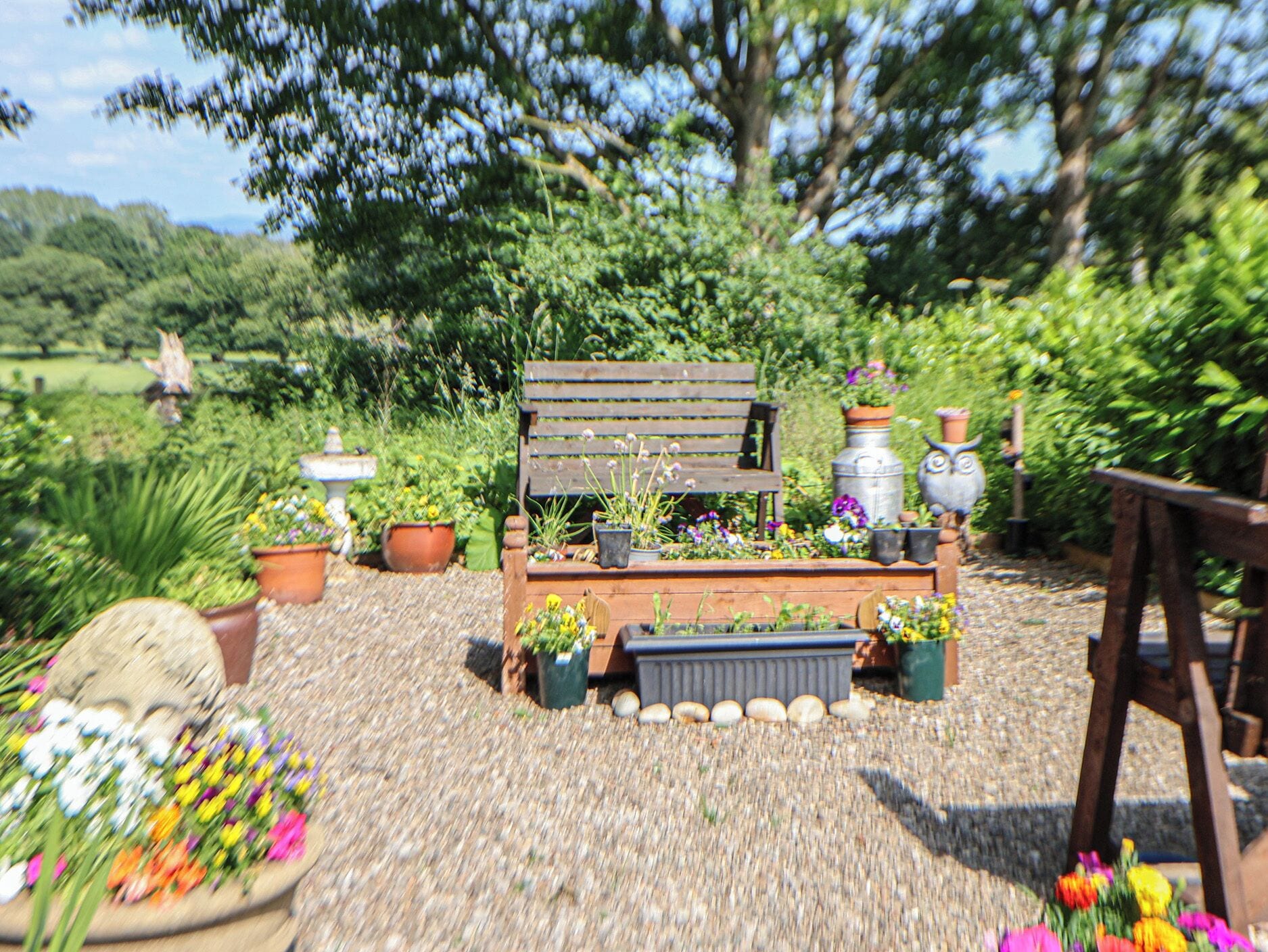 A garden with a wooden bench surrounded by potted plants and flowers.