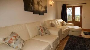 Una sala de estar con un sofá color beige, un sillón a juego y una alfombra oscura.