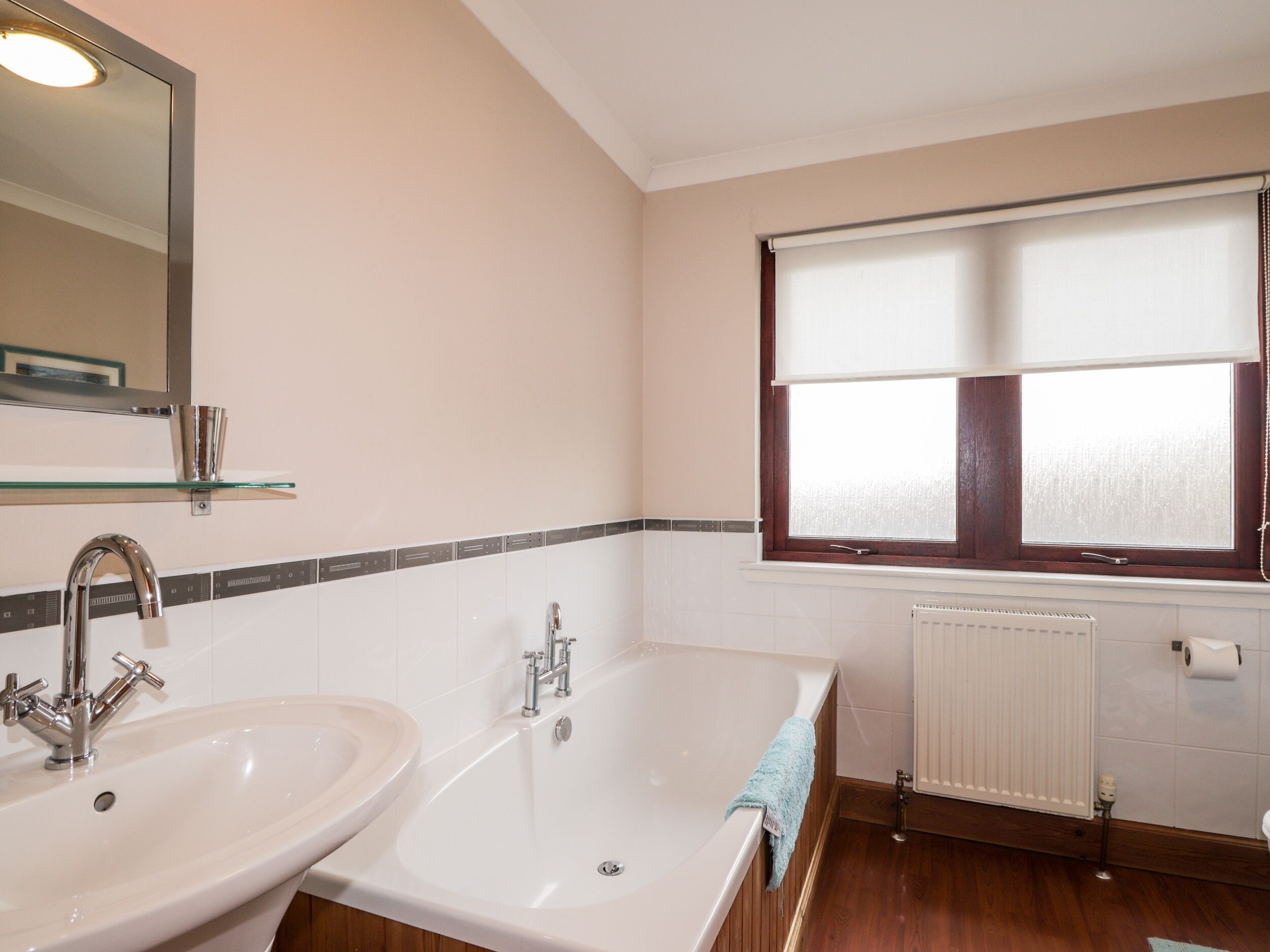 Ein Badezimmer mit zwei Waschbecken, einer Badewanne, einem Fenster mit Jalousien und einem Spiegel.